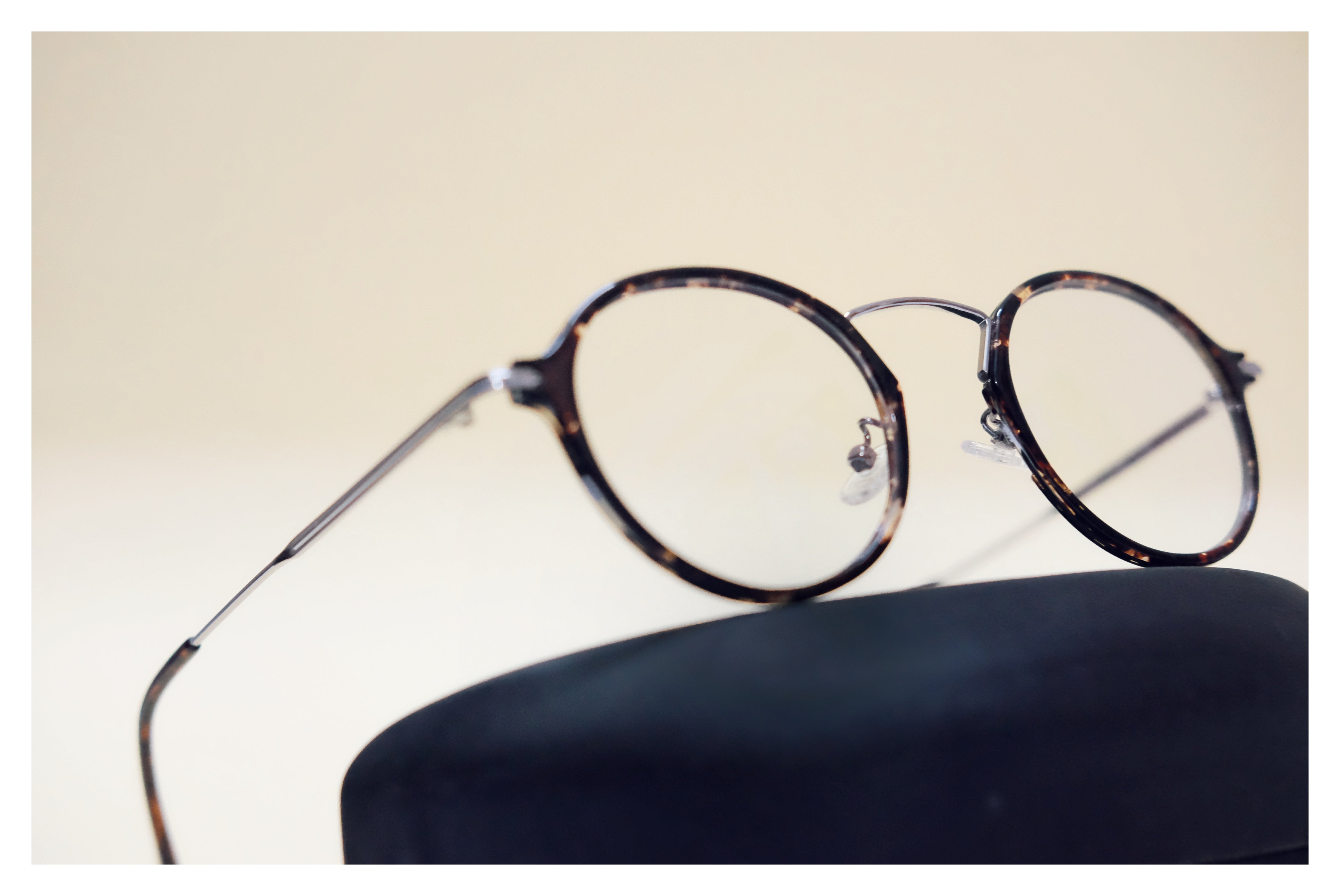 Round eyeglasses with tortoiseshell frame on a beige background